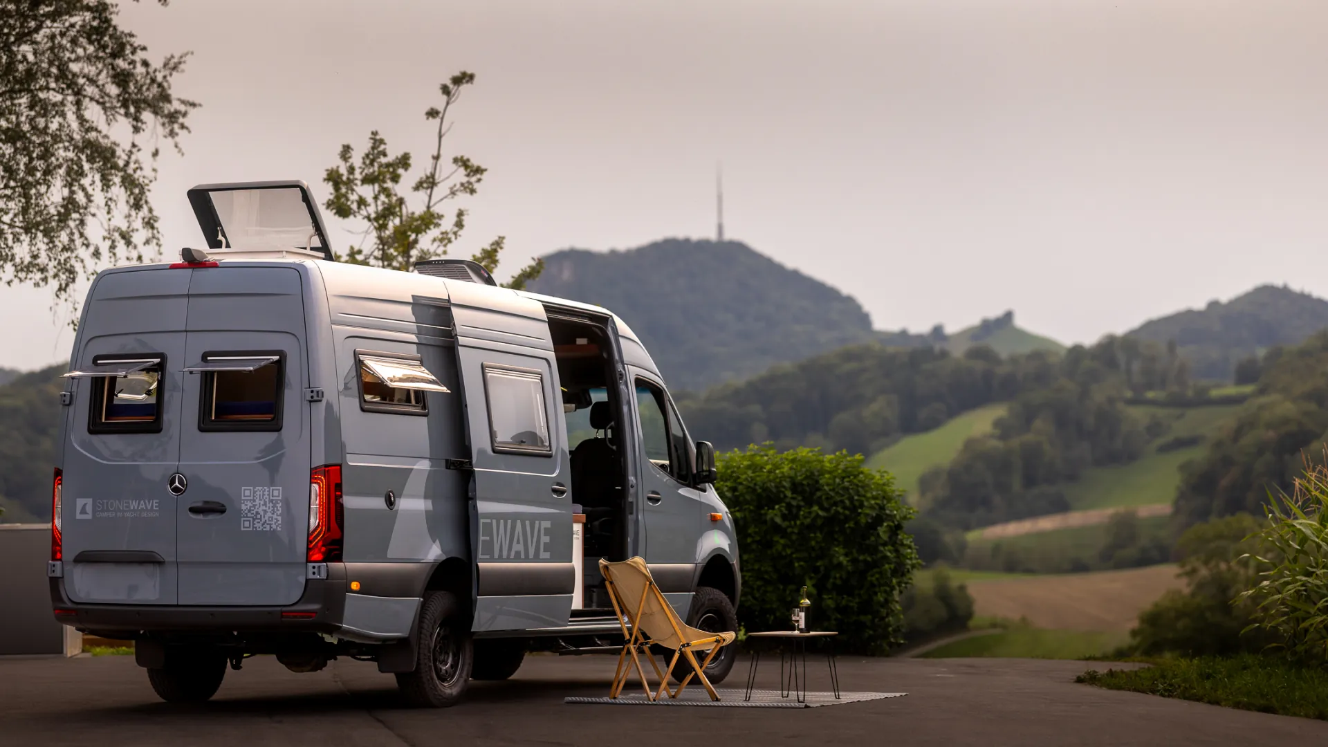 Stonewave Camper mit geöffnetem Innenraum in hügeliger Landschaft